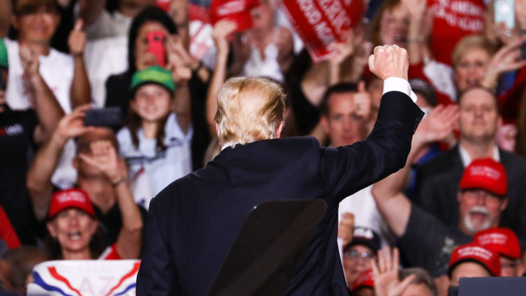 Donald Trump mit dem Rücken bei einer Wahlkampfveranstaltung zur Kamera vor Unterstützer*innen