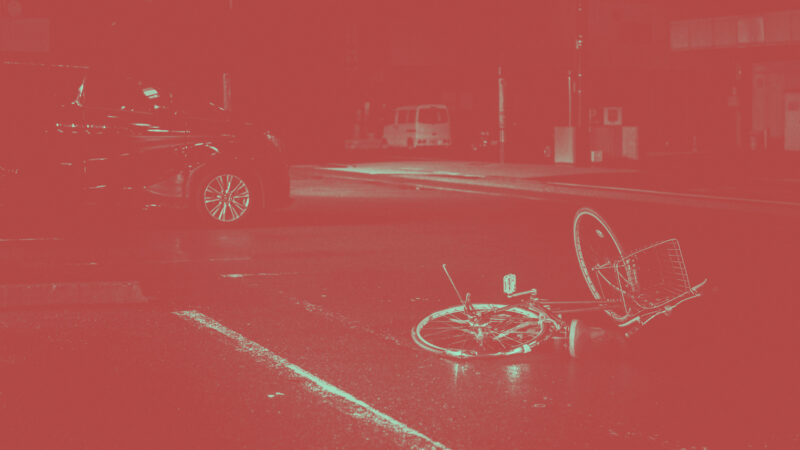 Farblich verfremdete Nachtaufnahme einer Unfallsituation. Keine sichtbaren Menschen, aber ein beschädigtes Fahrrad im Vordergrund, im Hintergrund ein Auto.