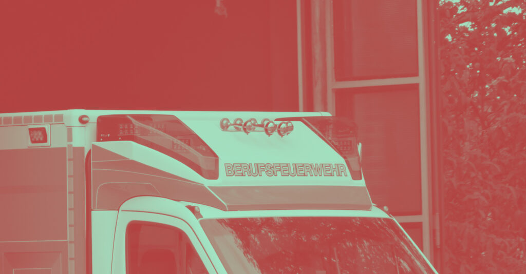 Farblich verfremdete Nahaufnahme des oberen Teils eines Krankenwagens, mit Blautlicht, Martinshorn und der Aufschrift „Berufsfeuerwehr“.
